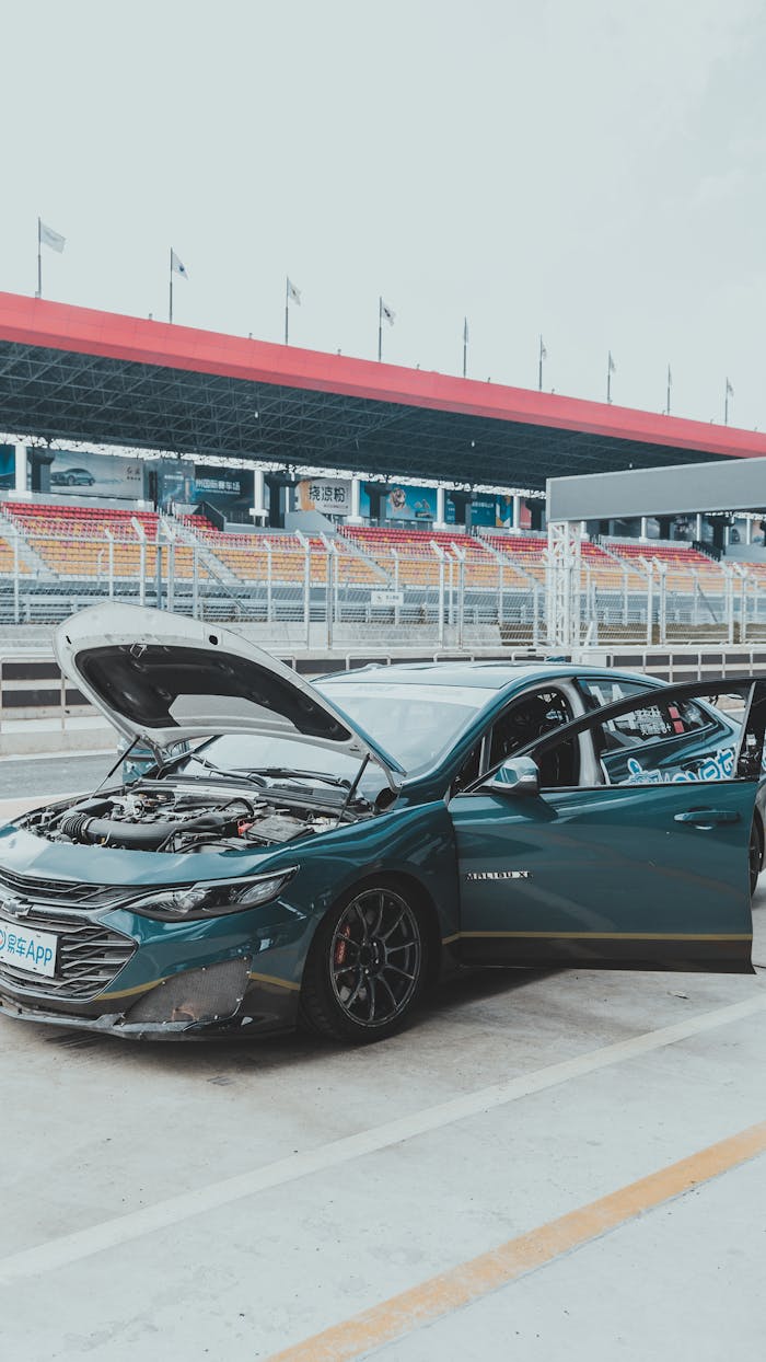 Car in a racing pit stop with hood open, ready for inspection or repair.